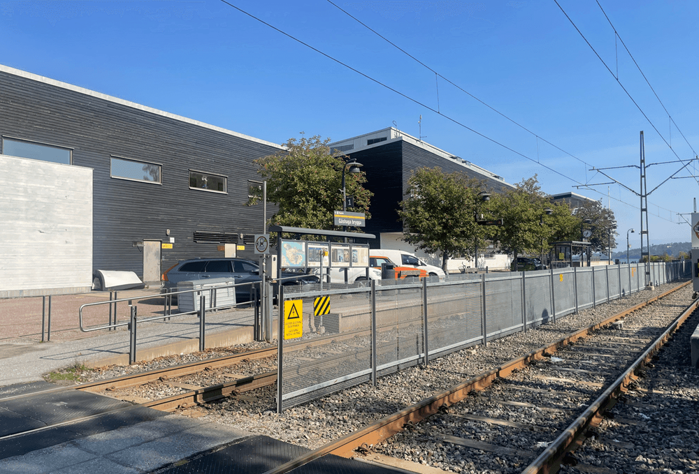 Byggnaden på Stapelbädden 9 sedd från söder med Lidingöbanan och hållplatsen Gåshaga brygga i förgrunden. 